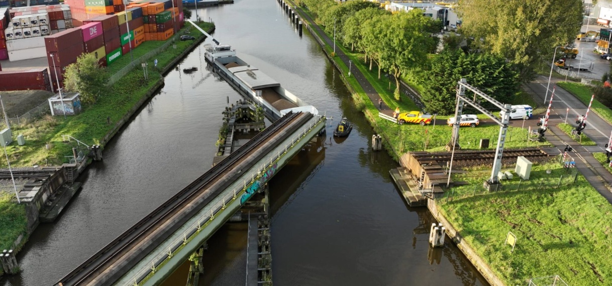 Schip ligt vast onder spoorbrug bij Alphen aan den Rijn na botsing