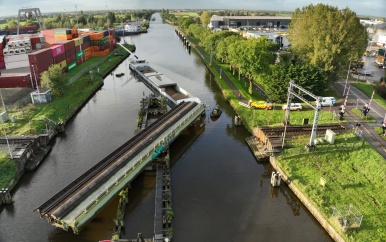 Schip ligt vast onder spoorbrug bij Alphen aan den Rijn na botsing