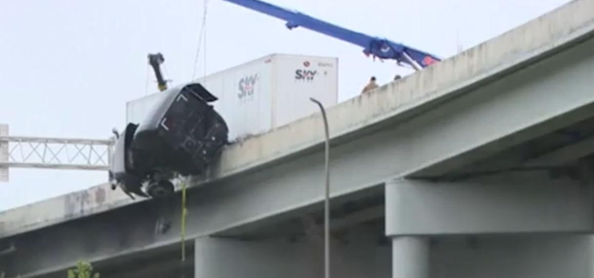 Chauffeur wordt uit truck getakeld die over brugreling hangt